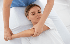 Physiotherapist helps a young female patient by Osteopathy method and massages her hand muscles